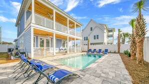 A two-story house with a pool, blue lounge chairs, and a covered patio area. - Joyful Sound by AvantStay | Walk to the Beach (Panama City Beach)