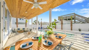 A wooden deck with a pool, outdoor seating, and a staircase leading to a deck. - Joyful Sound by AvantStay | Walk to the Beach (Panama City Beach)