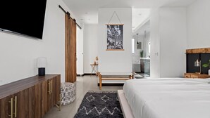 Un dormitorio moderno con una cama grande, un armario de madera, un televisor de pantalla plana y una obra de arte colgada.