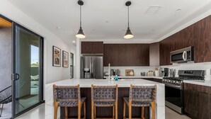 Una cocina moderna con armarios de madera oscura, electrodomésticos de acero inoxidable y una isla central con taburetes de bar.