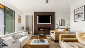 Una sala moderna con chimenea, un televisor de pantalla plana grande y un conjunto de sofás.