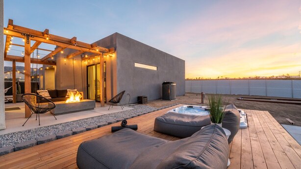 Un patio moderno al aire libre con una chimenea, asientos y un jacuzzi.