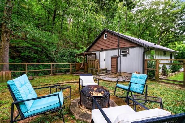 A cabin with a fire pit in the backyard, surrounded by outdoor furniture. - EV Cottage, Fenced Yard, Pets Free (Sevierville)