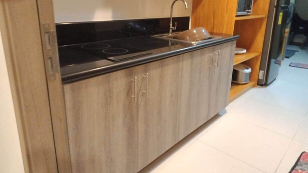 Una cocina con encimera negra, pileta de acero inoxidable y muebles de madera.