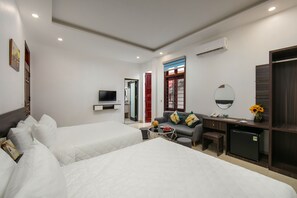 A hotel room with two beds, a desk, a small refrigerator, a TV, and a window with a view. - Hanoi Airport Suites Hostel & Travel (Hanoi)