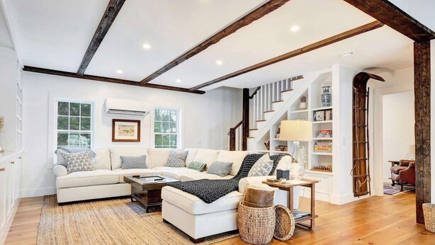A spacious living room with a white sofa, a coffee table, and a bookshelf. - Hillside Farmhouse, Updated & Pet-Friendly (Hartford)