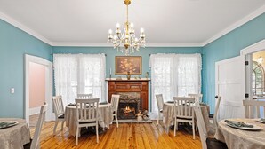 A dining room with a fireplace, wooden flooring, and white chairs. - The Steamboat Inn (Jefferson)