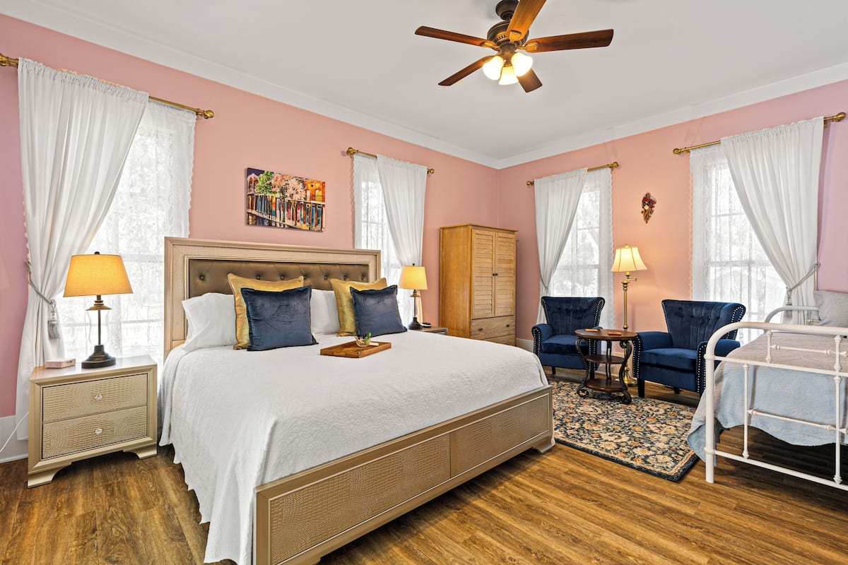 A bedroom with a large bed, two bedside tables, a wardrobe, a chair, and a ceiling fan.