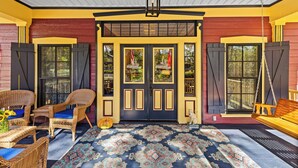 A porch with wicker furniture, a patterned rug, and a swing. - The Steamboat Inn (Jefferson)