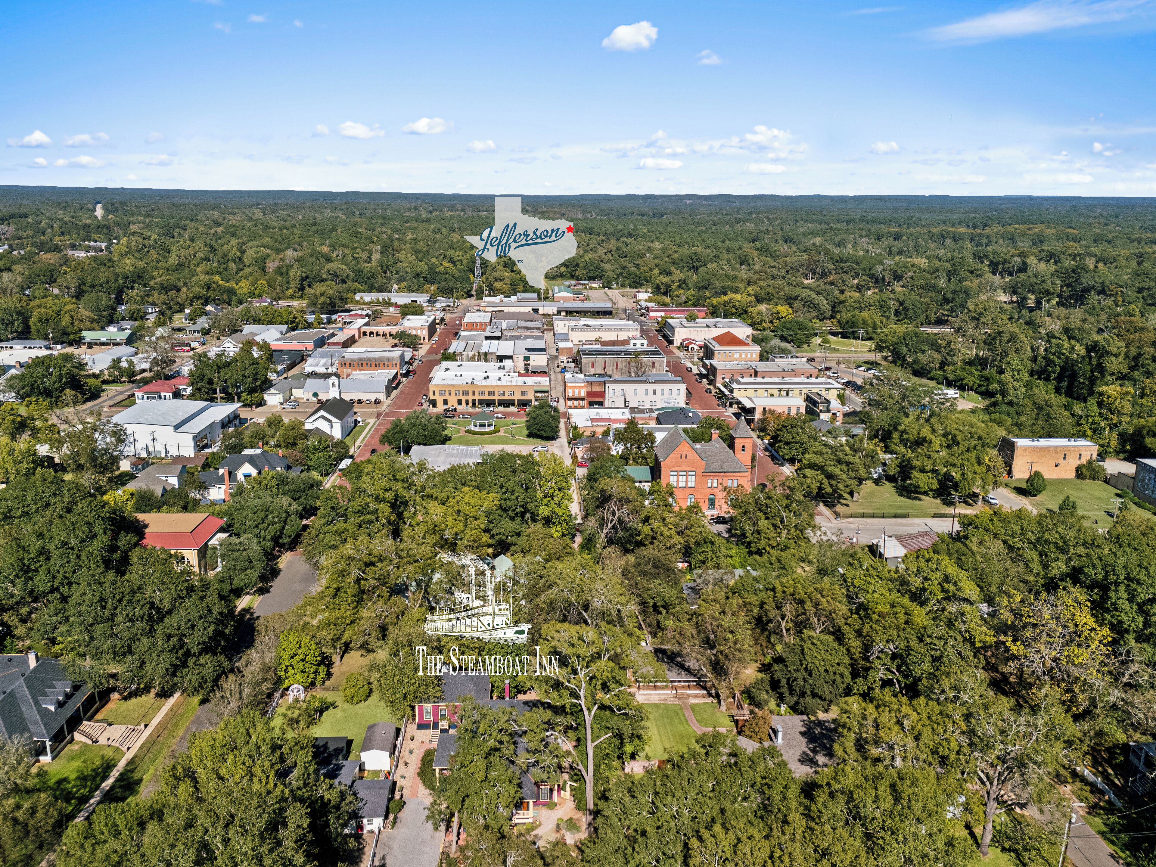 An aerial view of Jefferson, highlighting The Steamboat Inn surrounded by dense greenery and a mix of residential and commercial buildings.