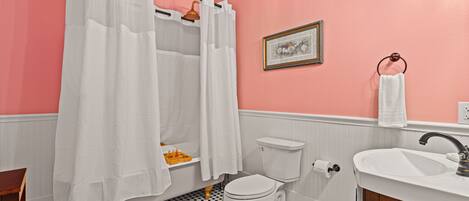 A bathroom with a white toilet, a sink, and a shower with a white curtain.