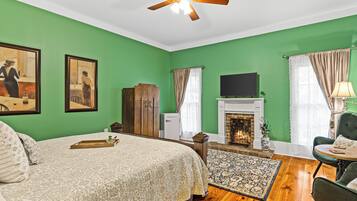 A room with a bed, a fireplace, a television, and green walls.