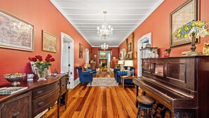 A hallway with wooden flooring, a chandelier, and a piano. - The Steamboat Inn (Jefferson)