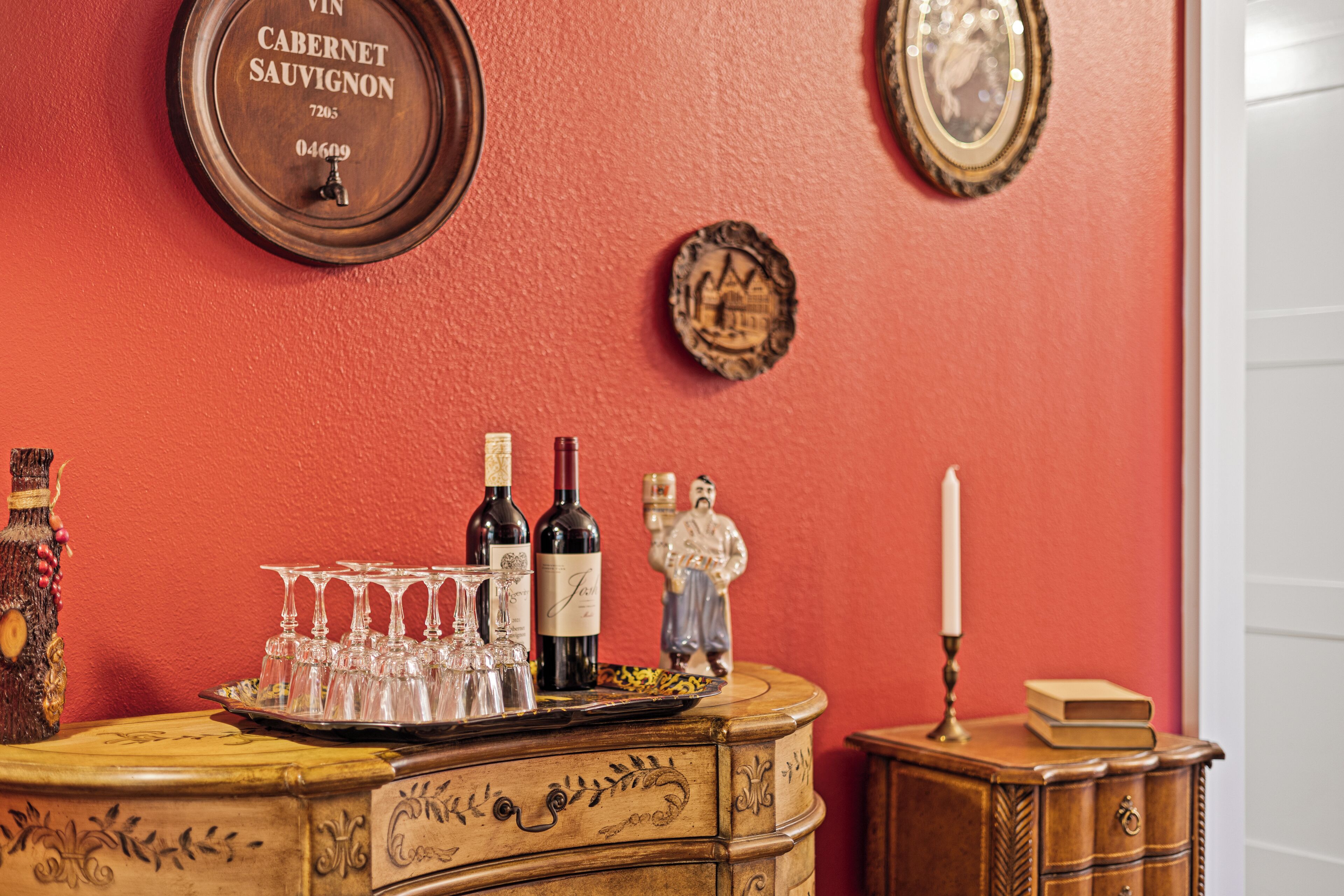 A wooden bar counter with wine bottles, glasses, and a candle.