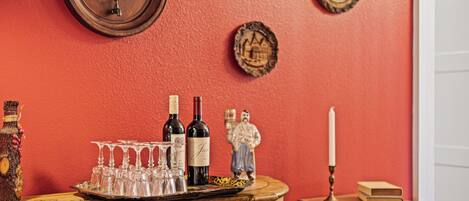 A wooden bar counter with wine bottles, glasses, and a candle.
