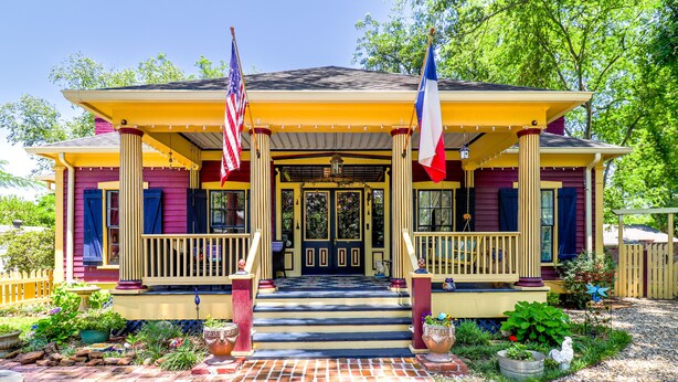 A two-story house with a porch, a front door, and a flagpole. - The Steamboat Inn (Jefferson)