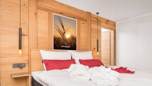 Une chambre d’hôtel moderne avec une tête de lit en bois, un lit recouvert d’une literie blanche et rouge, et une affiche représentant des champs de blé.