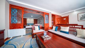 A hotel room with a wooden sofa, a small table with a bottle, a radiator, and a patterned carpet.