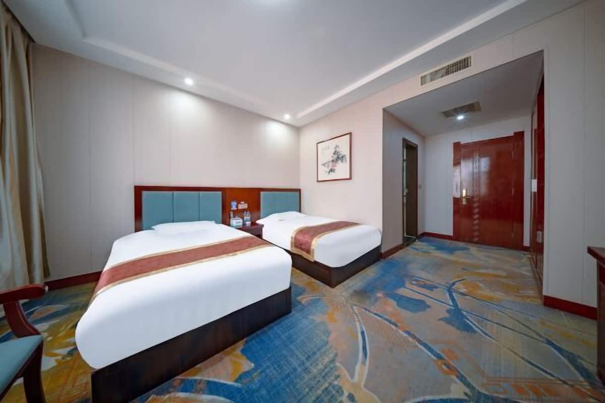 Ein Hotelzimmer mit zwei Betten, einem großen Fenster und Teppichboden.