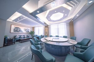 Una sala de conferencias moderna con una mesa redonda, asientos cómodos e iluminación empotrada en el techo.