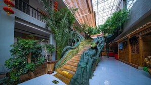 Un vaste atrium doté d’un escalier central, entouré d’une végétation luxuriante et agrémenté d’une décoration traditionnelle.