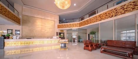 A spacious lobby with a reception desk, seating area, and a large chandelier.