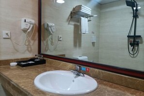 Une salle de bain équipée d’un lavabo, d’un miroir, d’un sèche-cheveux et d’un porte-serviettes.