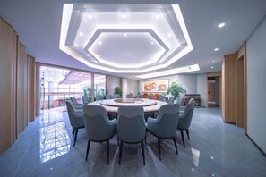 Un comedor moderno con una mesa redonda y sillas, una lámpara de techo hexagonal y ventanas grandes.