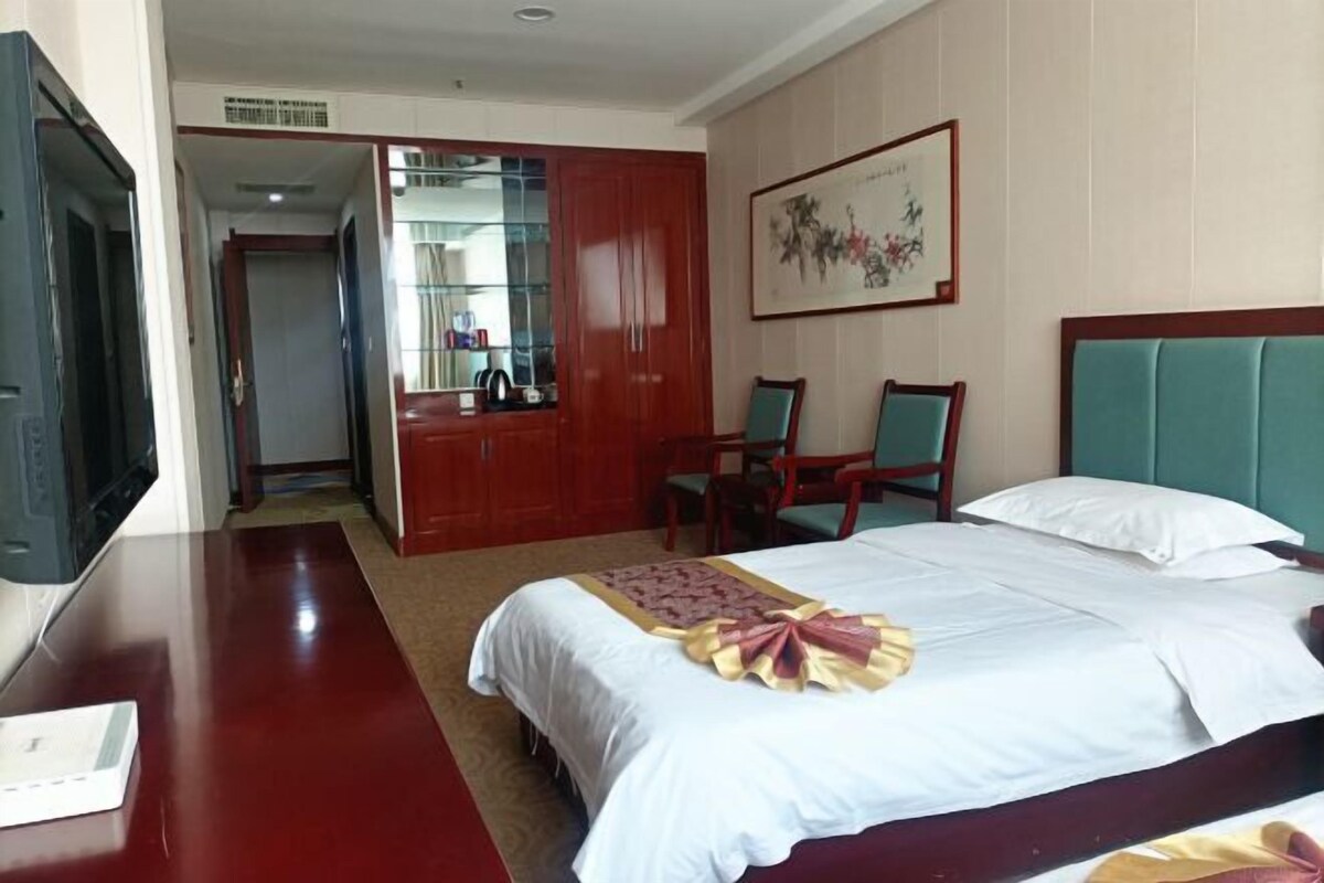 Une chambre d’hôtel comprenant un lit, un bureau, une télévision, une armoire et une chaise.