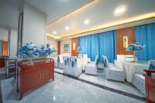 Habitación de hotel con zona de comedor, aparador de madera y cortina azul.