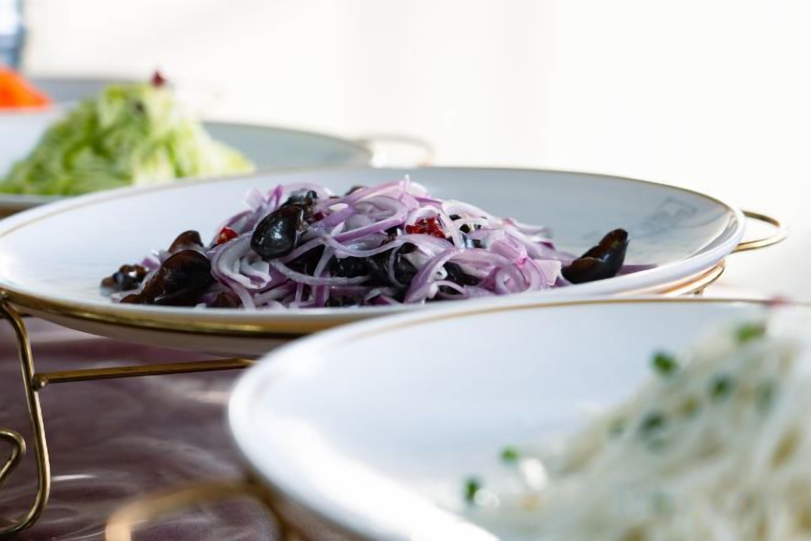 Ein Teller Essen mit roten Zwiebeln und schwarzen Oliven.