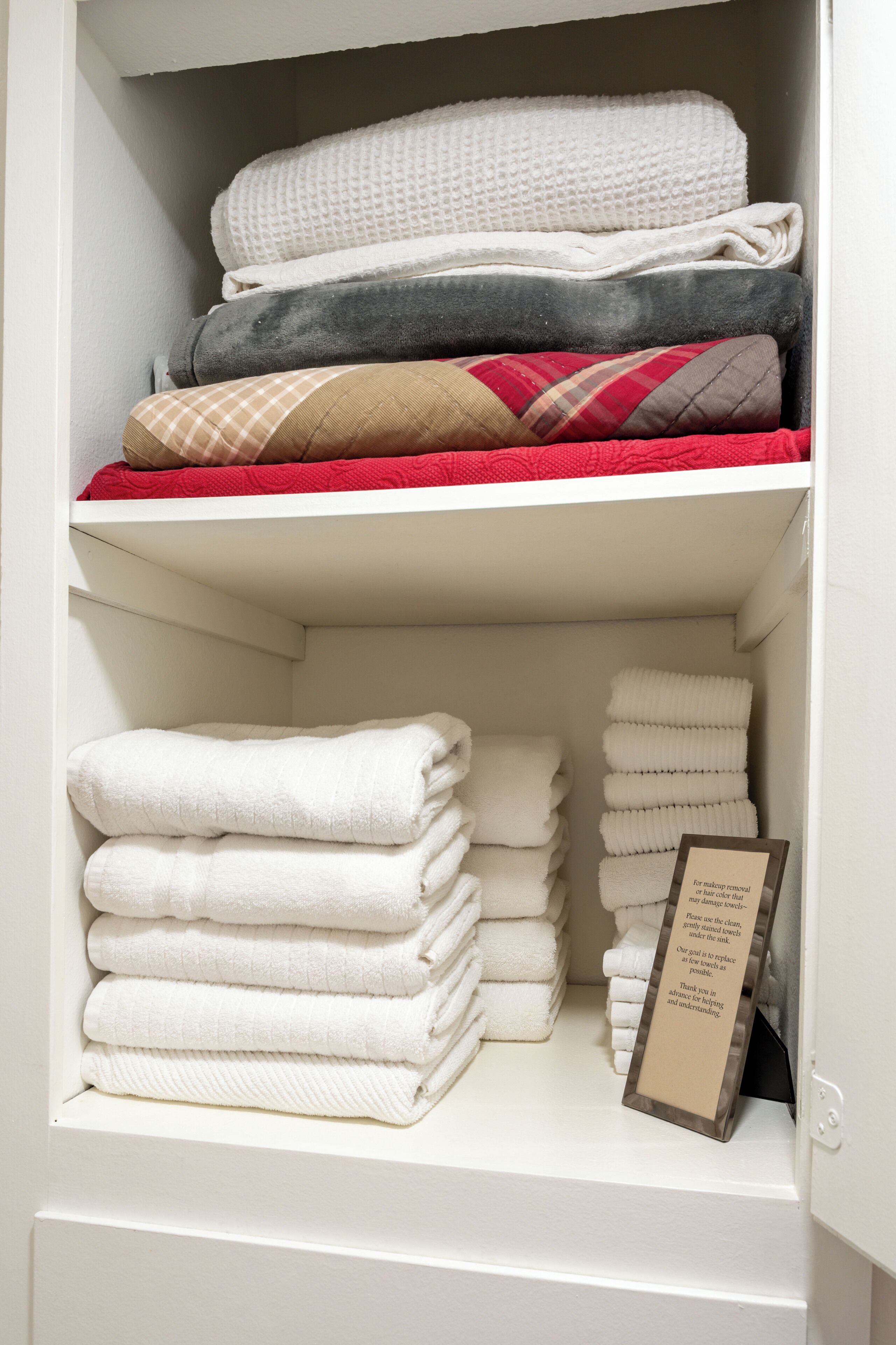 A neatly organized shelf with folded towels in various colors and patterns.