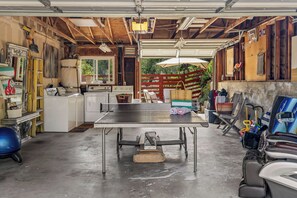 A garage with a ping pong table, various tools, and a bicycle.