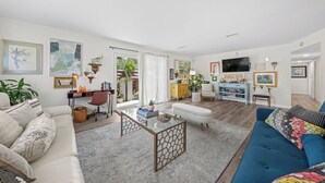 Un salon moderne comprenant un canapé, une table basse, un téléviseur et un bureau.