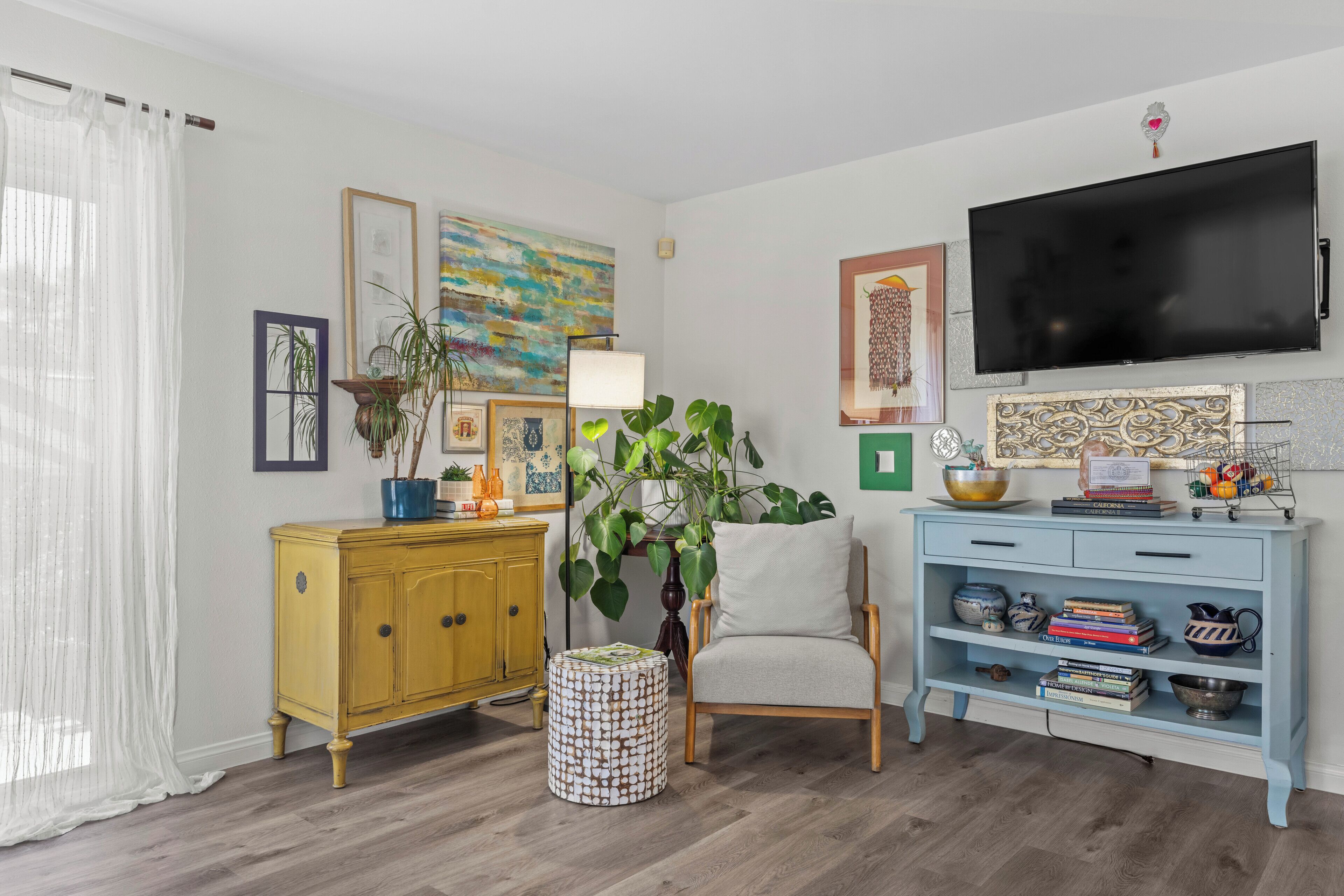 A living room with a TV, a sofa, a coffee table, a cabinet, and a plant.