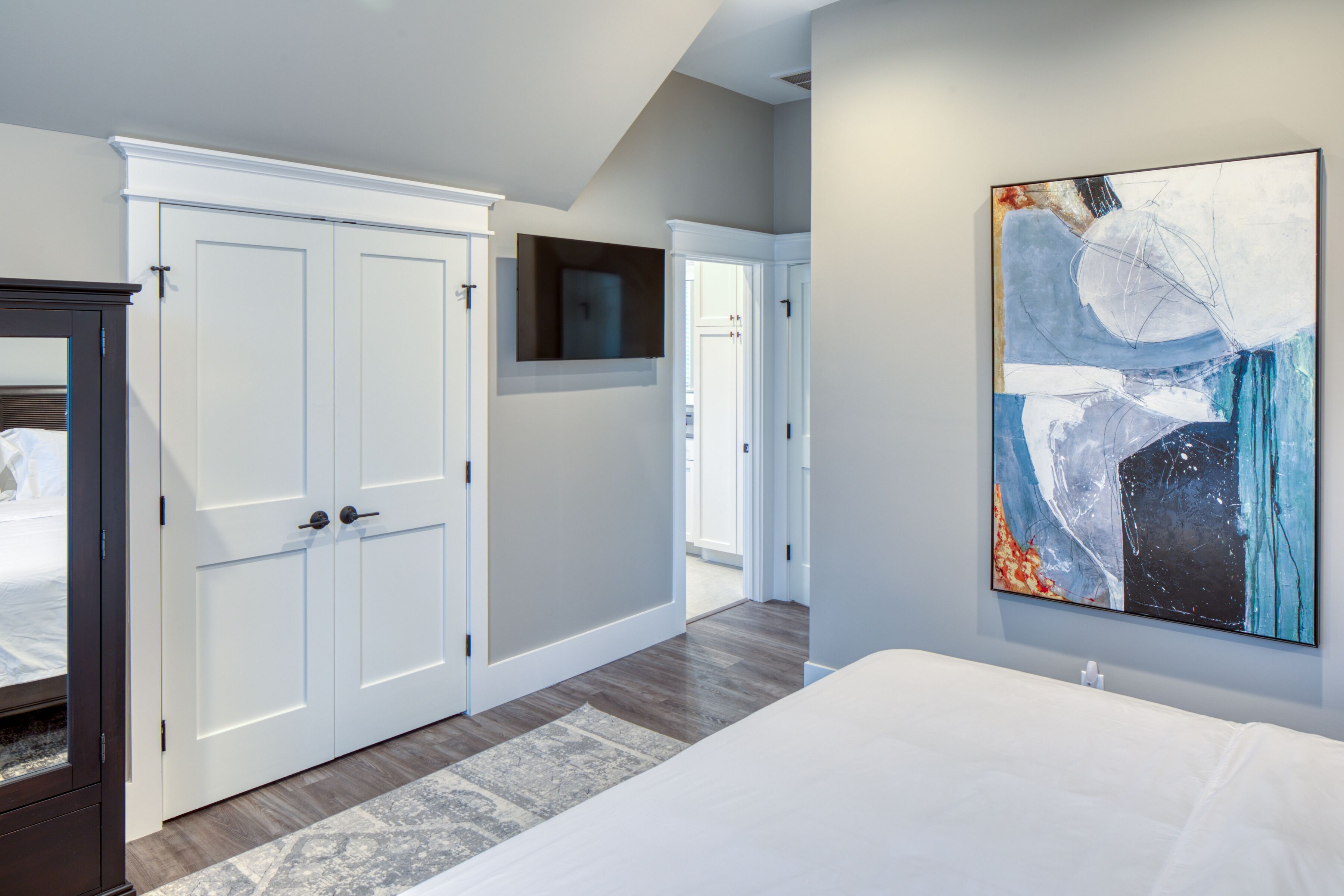 A bedroom with a large bed, a wardrobe, and a painting on the wall.
