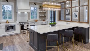 A modern kitchen with a large island, stainless steel appliances, and a hanging light fixture. - Lake Views  + Porch Movies, Game Nights and Hot Tub (Bluffton)