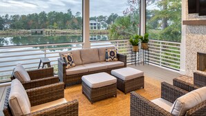 A spacious outdoor seating area with wicker furniture and a view of a lake and trees. - Lake Views  + Porch Movies, Game Nights and Hot Tub (Bluffton)