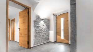 Un pasillo con pared de piedra decorativa, puertas de madera y suelo de baldosas.