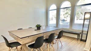 Una sala de conferències amb un gran taulell de fusta, quatre cadires negres, una banca i una planta en test.