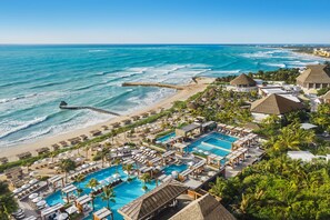 Ett semesterkomplex med flera pooler, en strand och en brygga.