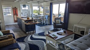 A spacious living area with a kitchen, dining table, and a comfortable seating arrangement.