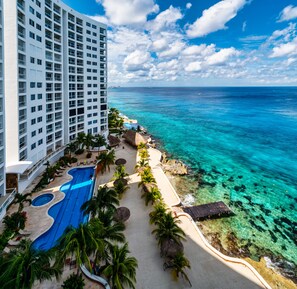 Ein Resort mit großem Pool, Palmen und Blick auf den Ozean.
