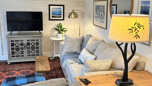 Una sala de estar con un sofá, una mesa de centro, un televisor y una lámpara.