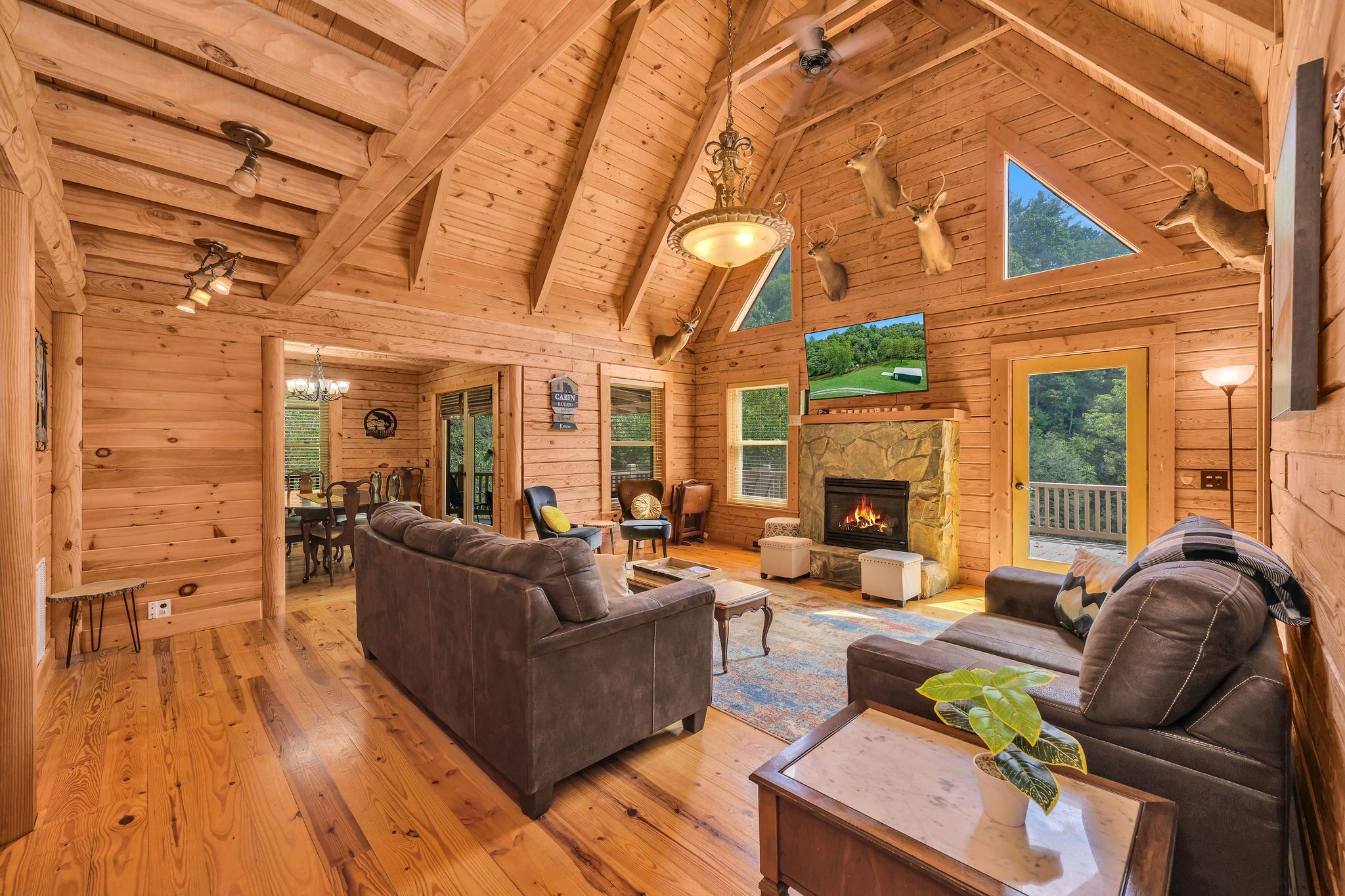 A log cabin interior with a fireplace, wooden floors, and a dining area.