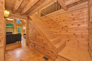 Ein Holzinnenraum mit Treppe, Kamin und Fernseher.