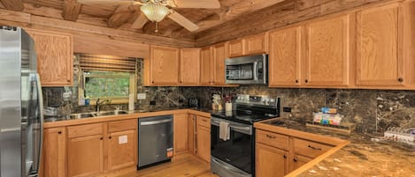 Una cocina con armarios de madera, un refrigerador de acero inoxidable, un microondas, un horno y un lavavajillas.
