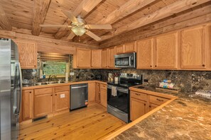 A kitchen with wooden cabinets, a stainless steel refrigerator, a microwave, an oven, and a dishwasher.
