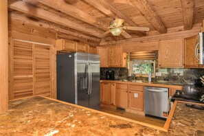 Una cocina con armarios de madera, un refrigerador de acero inoxidable, un lavavajillas y un ventilador de techo.