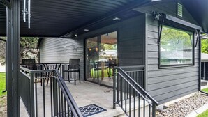 A covered outdoor area with a concrete floor, metal railings, and a set of stairs leading to a door. - Pets & Kids Love this Montana Dream Home! (Billings)